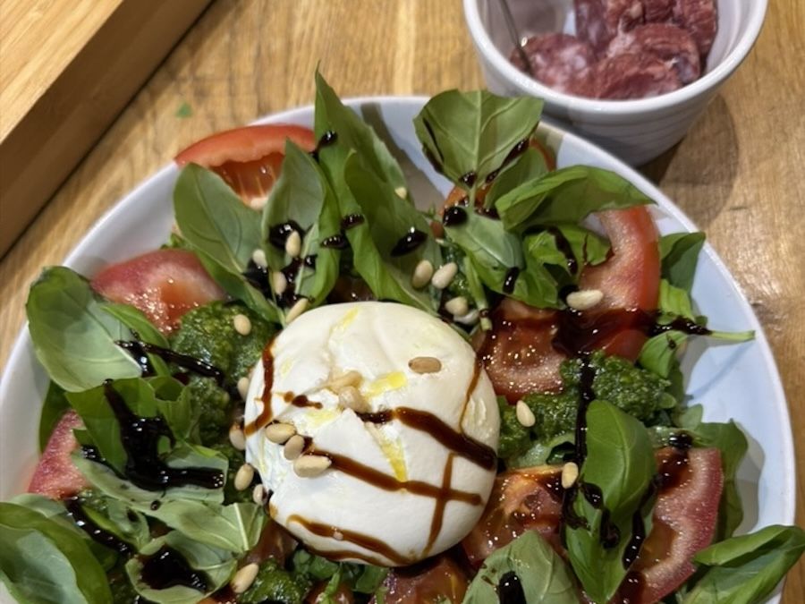 A plate of salad with burrata, tomatoes and basil